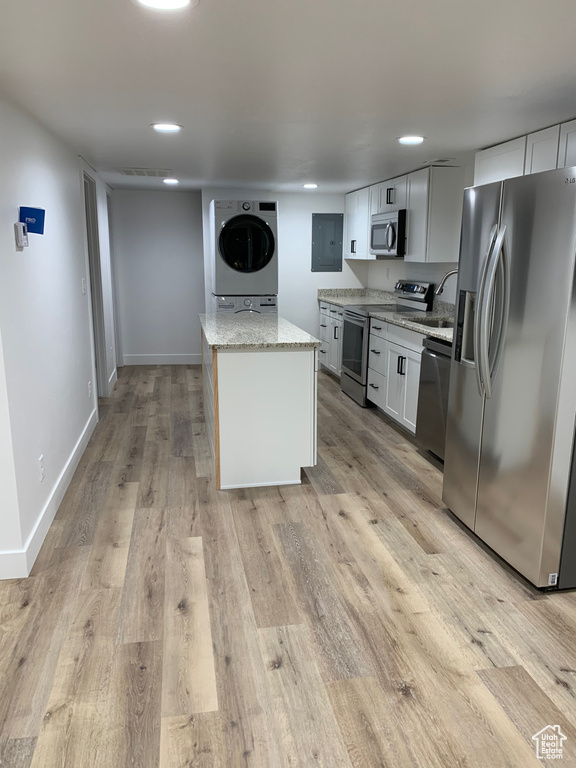 Kitchen with appliances with stainless steel finishes, light wood-style flooring, light stone counters, a kitchen island, and recessed lighting