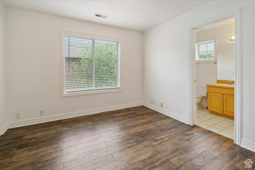 Unfurnished room with wood-type flooring, a sink, and baseboards