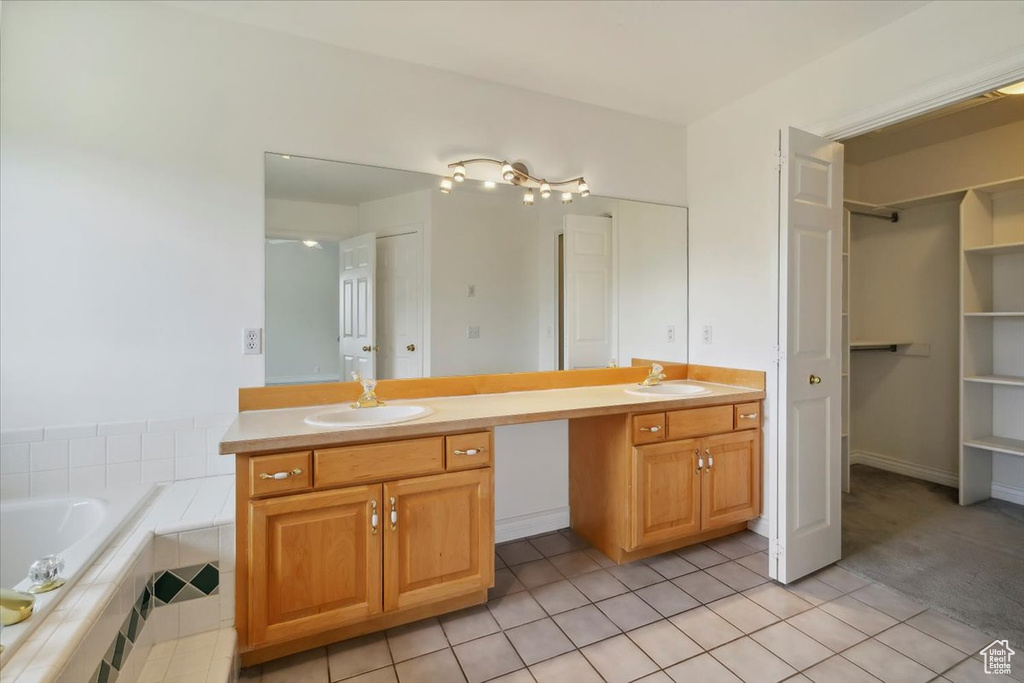 Bathroom featuring double vanity, tile patterned flooring, and a relaxing tiled tub
