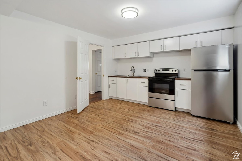 Kitchen featuring appliances with stainless steel finishes, dark countertops, a sink, and light wood-style floors