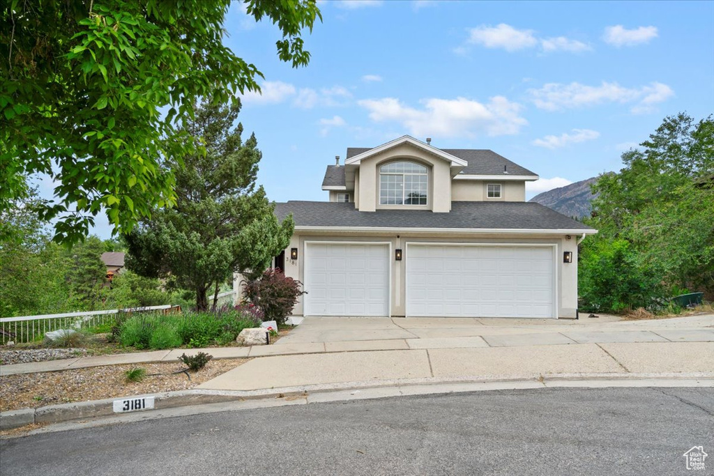 Traditional-style home with stucco siding, concrete driveway, roof with shingles, and a garage