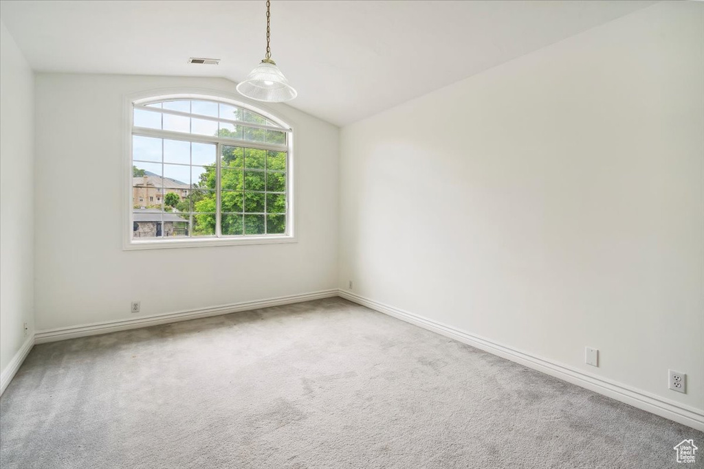 Carpeted spare room with lofted ceiling and baseboards