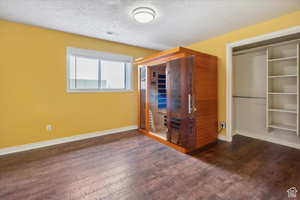 Unfurnished bedroom with dark wood-type flooring, baseboards, and a textured ceiling