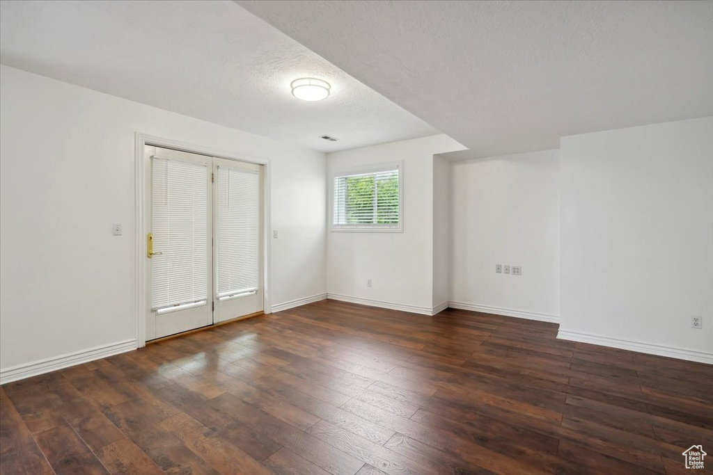 Spare room featuring wood-type flooring, baseboards, and a textured ceiling