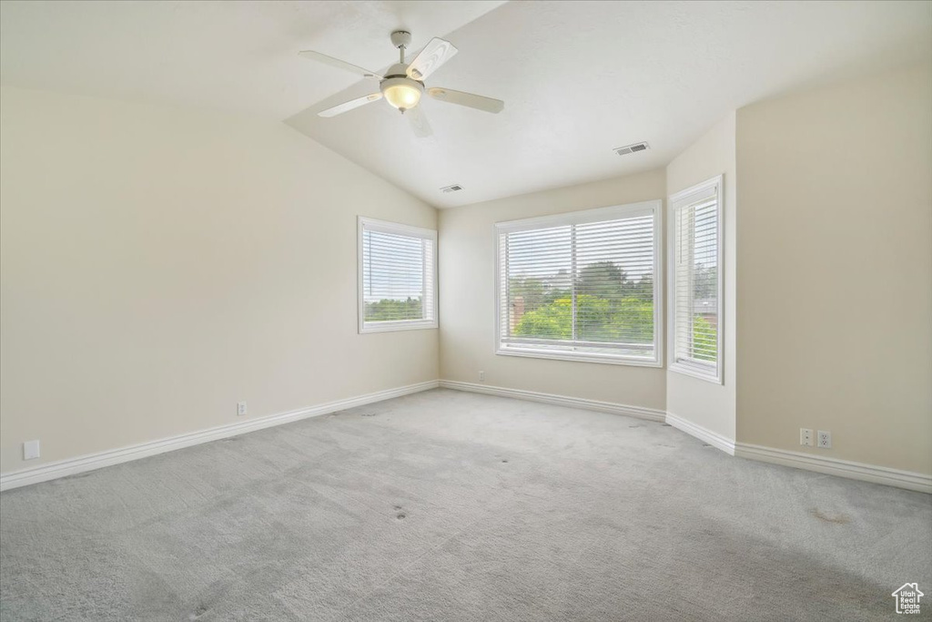 Carpeted empty room featuring ceiling fan, baseboards, and lofted ceiling