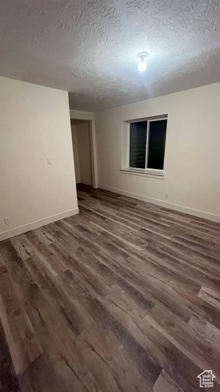 Unfurnished room featuring dark wood-type flooring and a textured ceiling