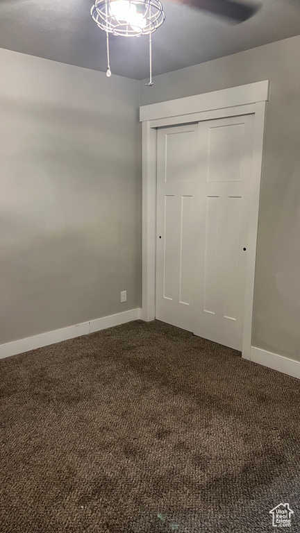 Unfurnished bedroom with dark colored carpet, a closet, and ceiling fan