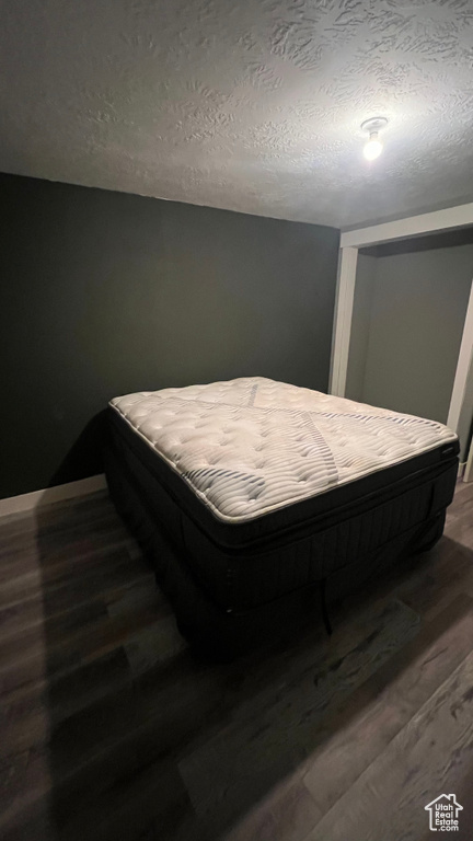 Bedroom featuring a textured ceiling and dark wood-style floors