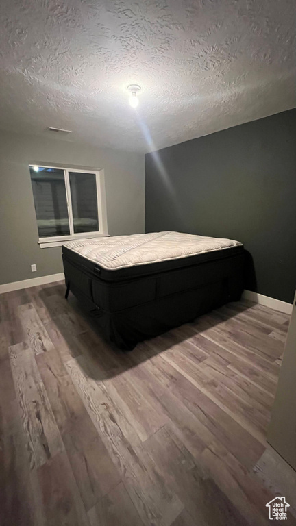 Bedroom featuring wood finished floors and a textured ceiling