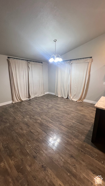 Unfurnished dining area with a chandelier, dark wood-type flooring, and lofted ceiling