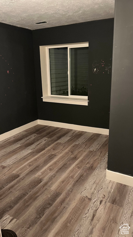 Empty room featuring wood finished floors and a textured ceiling