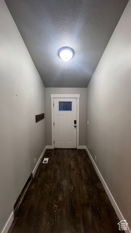 Doorway featuring a textured ceiling and wood finished floors