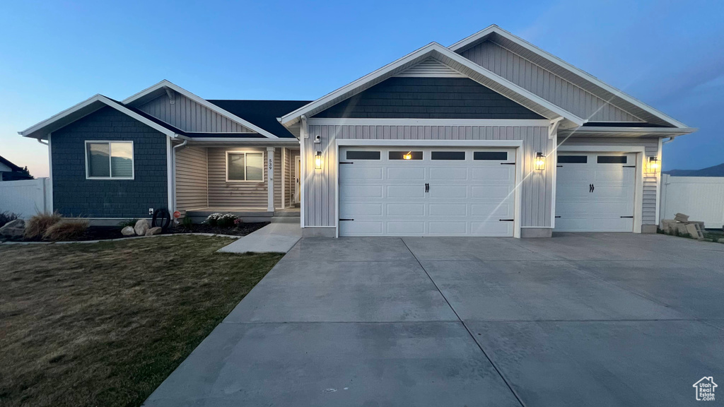 View of front of home featuring an attached garage, board and batten siding, driveway, and a front lawn