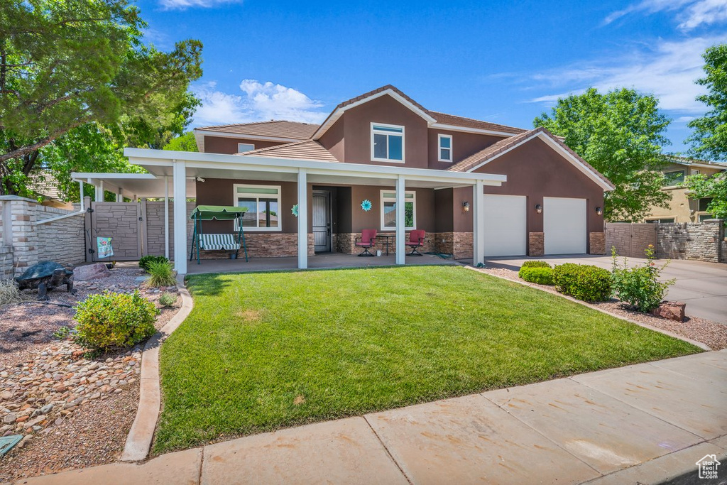 Traditional-style home featuring stone siding, stucco siding, driveway, an attached garage, and a porch