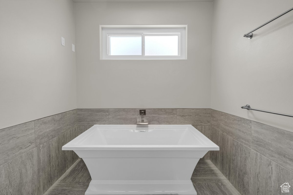 Bathroom featuring tile walls, a soaking tub, and a wainscoted wall