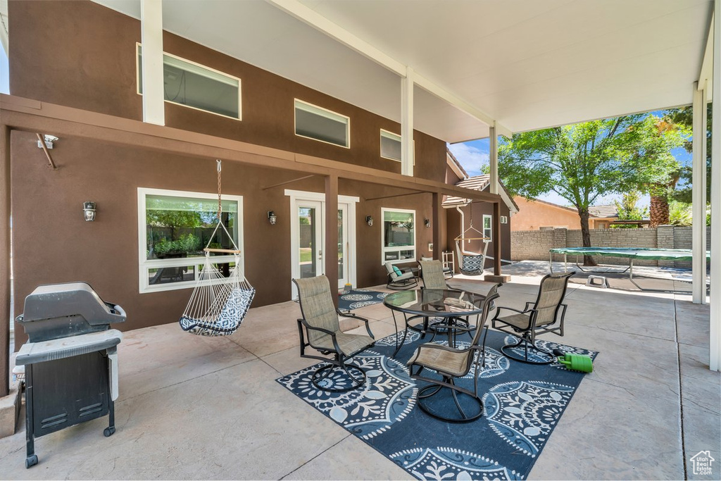View of patio featuring a trampoline, grilling area, and outdoor dining area
