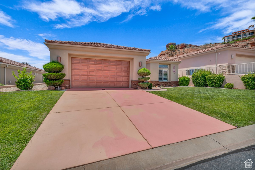 Mediterranean / spanish home featuring a garage, a tile roof, driveway, and a front yard