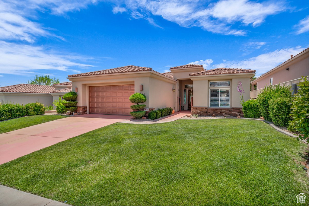 Mediterranean / spanish-style home featuring a garage, stucco siding, driveway, and stone siding