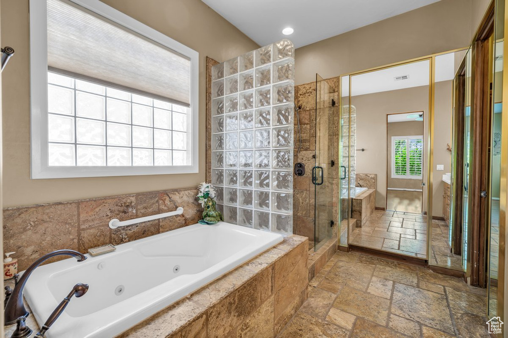 Bathroom with stone tile flooring, a shower stall, a tub with jets, and vanity