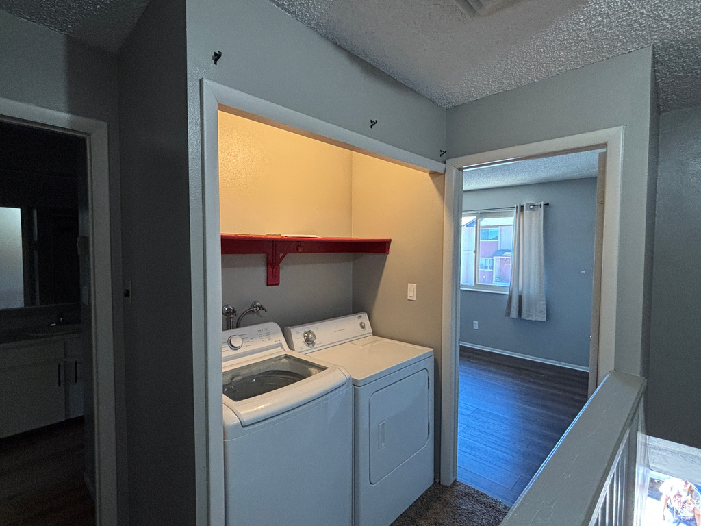 Laundry room featuring washer and clothes dryer, a textured ceiling, and dark wood finished floors