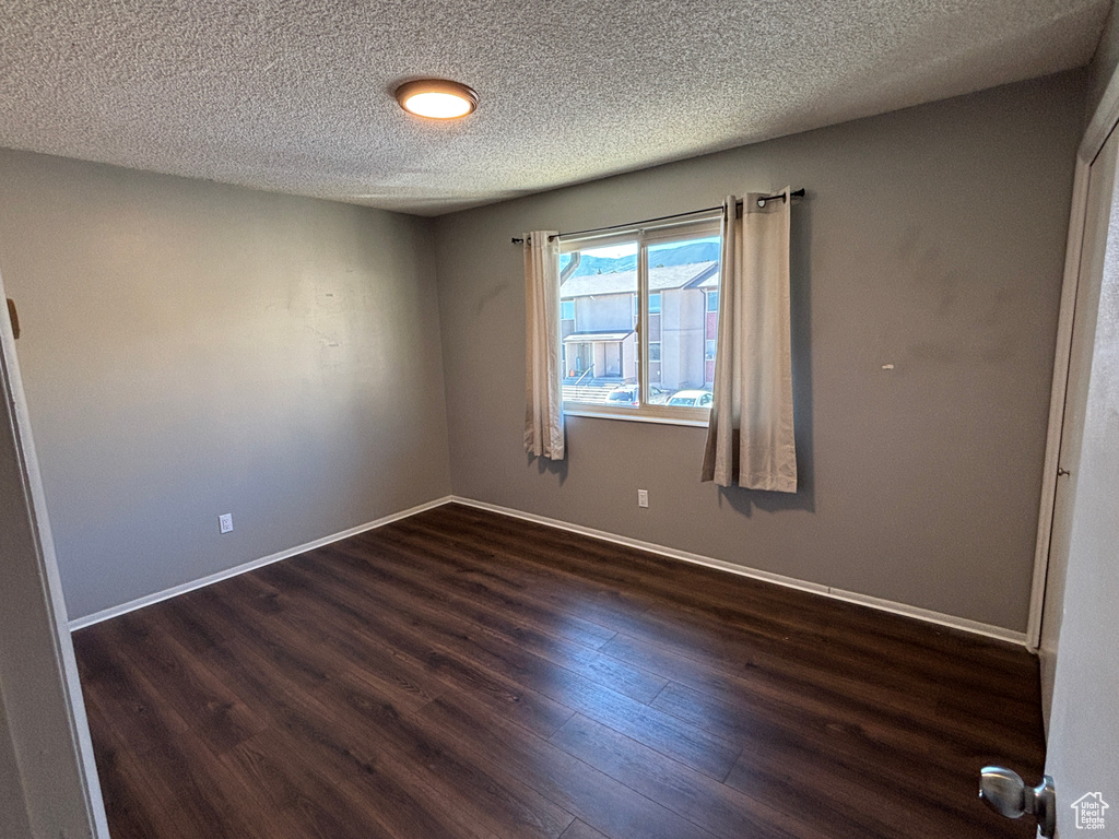 Unfurnished room with dark wood-type flooring and a textured ceiling