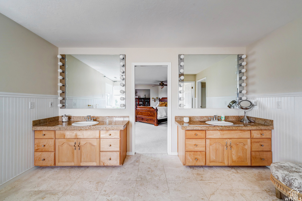 Bathroom with ensuite bath, a wainscoted wall, two vanities, and ceiling fan