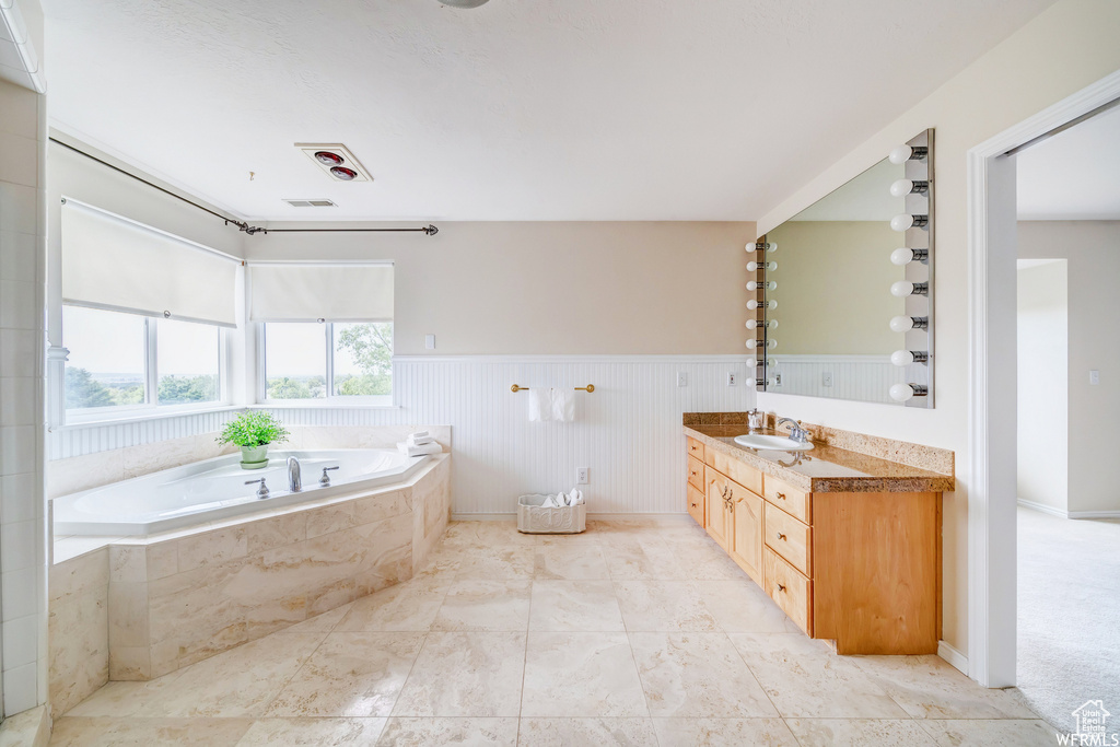 Full bathroom with vanity, a bath, and a wainscoted wall