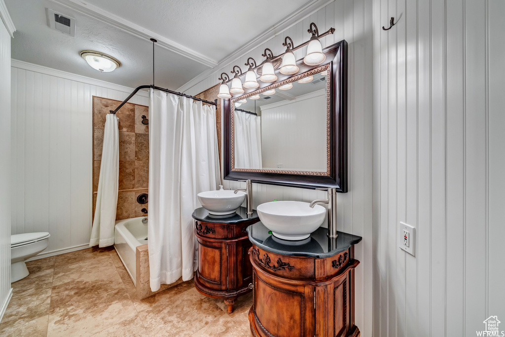 Bathroom with shower / bath combo with shower curtain, vanity, and crown molding