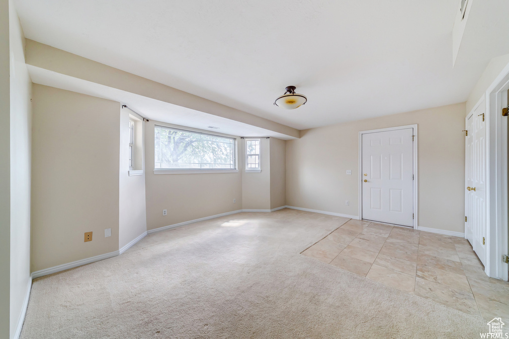 Empty room with light colored carpet and baseboards