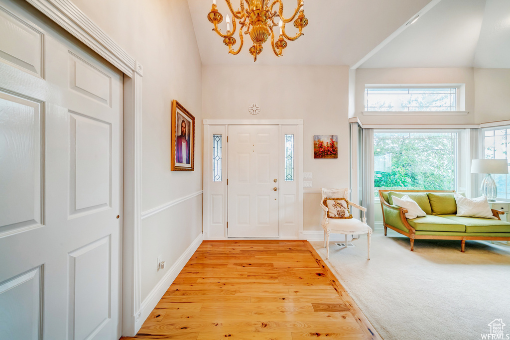 Entrance foyer with high vaulted ceiling, a chandelier, and light wood finished floors