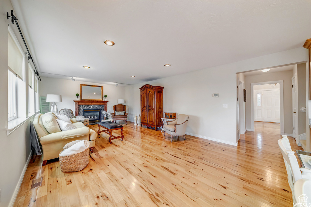 Living area featuring light wood-style floors, a glass covered fireplace, and recessed lighting