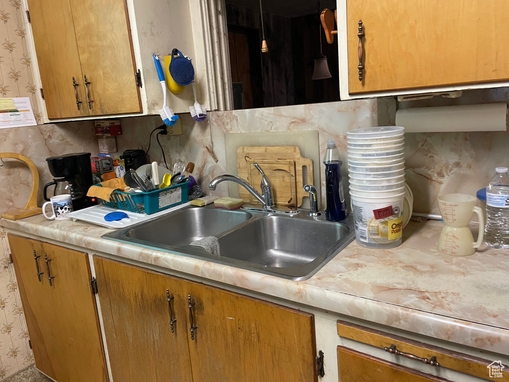 Kitchen with wallpapered walls, light countertops, and brown cabinetry