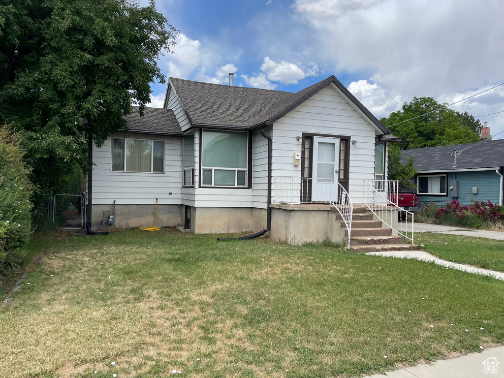 Bungalow featuring a front yard, a shingled roof, and a gate
