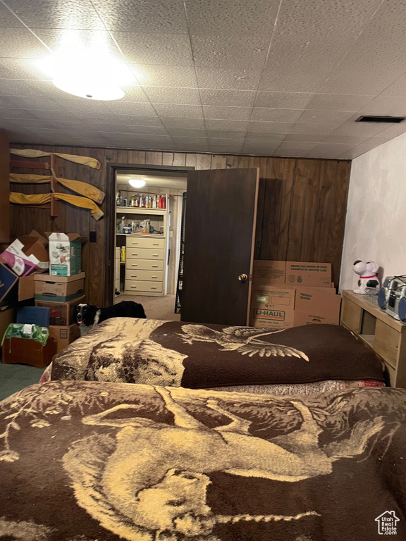 Carpeted bedroom featuring wood walls
