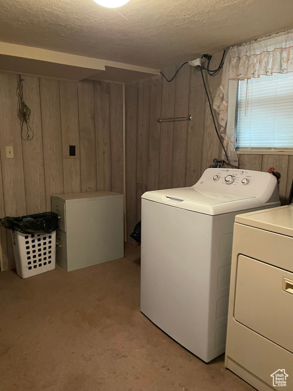 Washroom with wood walls, washing machine and clothes dryer, and a textured ceiling