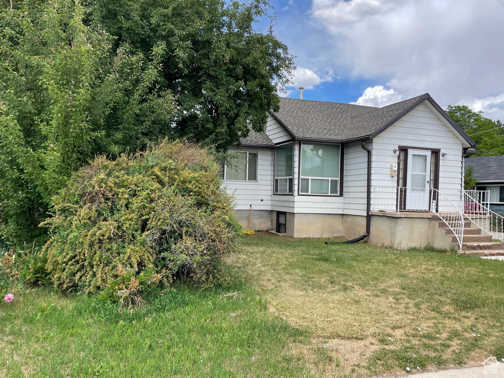 View of front of home with a shingled roof and a front yard