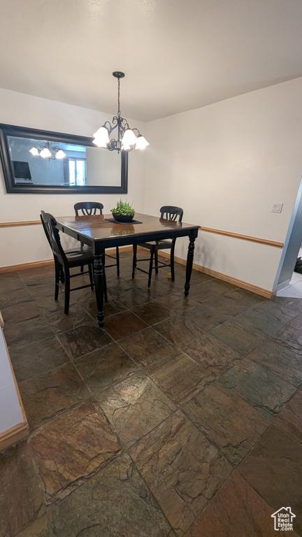 Dining space featuring dark stone finish floors and a chandelier