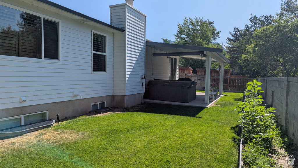 Fenced backyard featuring a hot tub and a patio area
