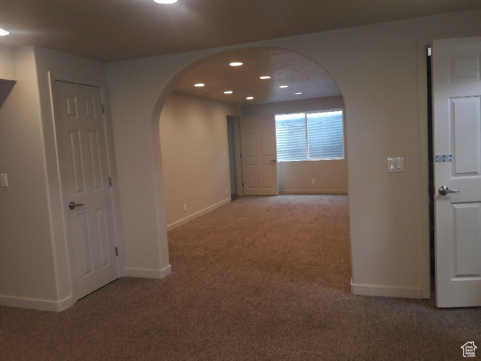 Hallway with carpet, arched walkways, and recessed lighting