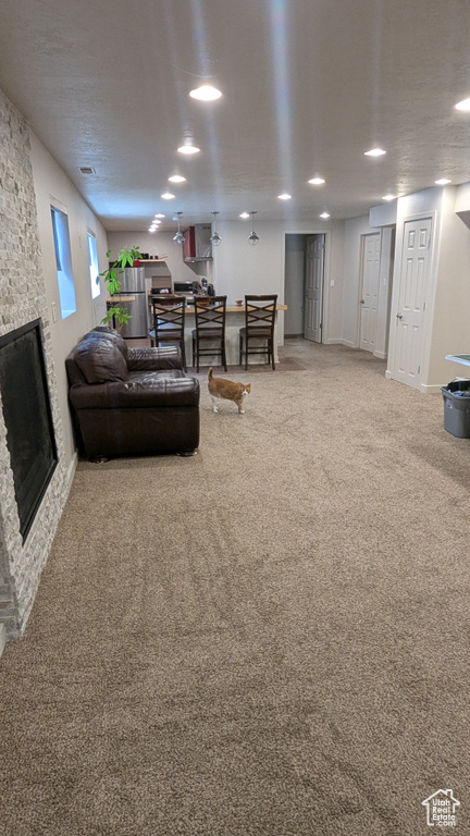 Living room featuring carpet floors and a stone fireplace