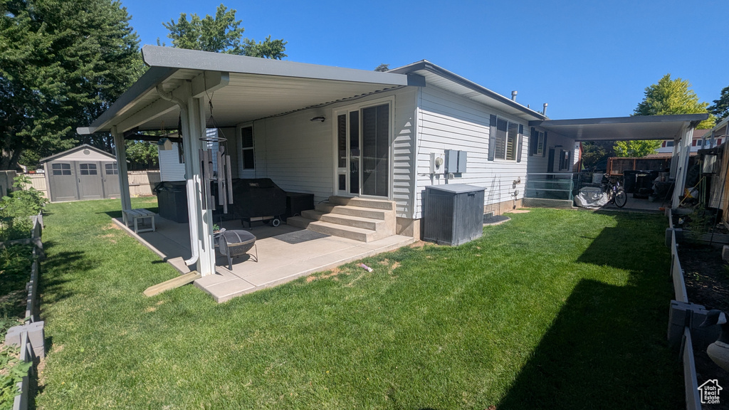 Rear view of house with entry steps, a storage shed, and a patio