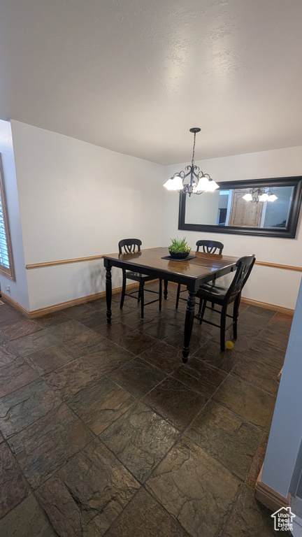 Dining room featuring stone tile flooring and a chandelier
