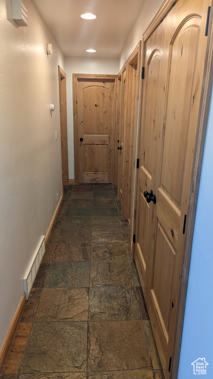 Corridor with stone tile flooring and recessed lighting