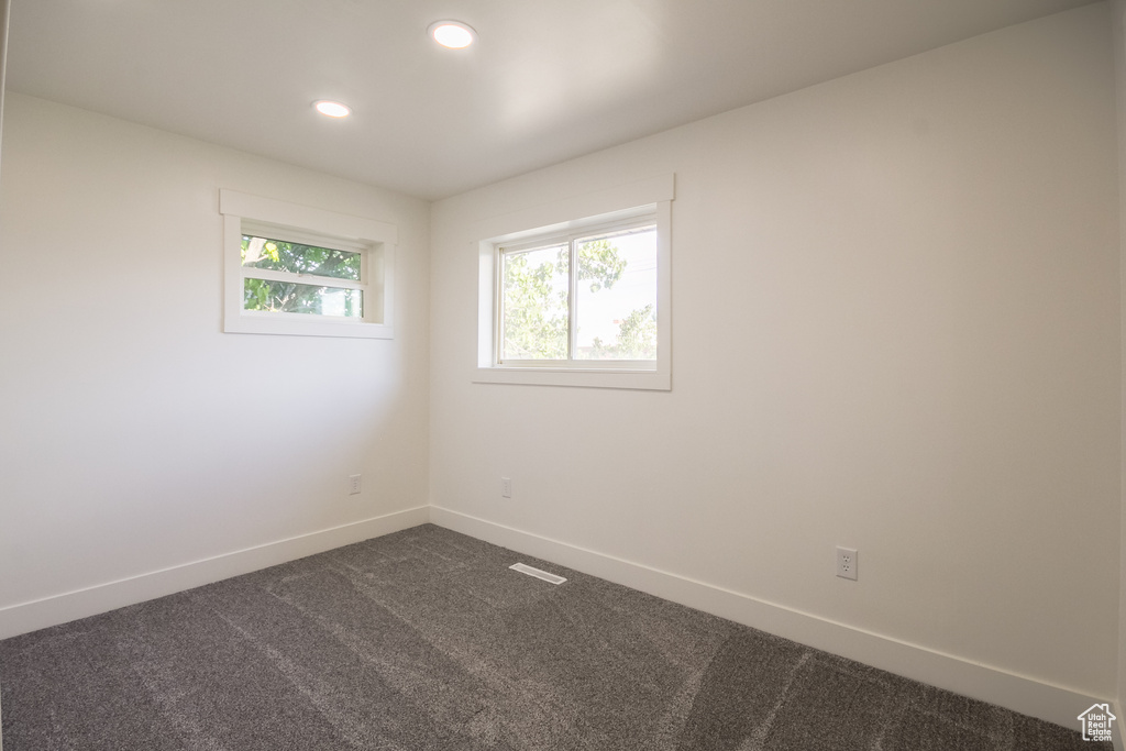Empty room with dark colored carpet and recessed lighting