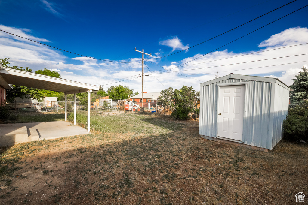 View of grassy yard featuring a storage shed and a patio