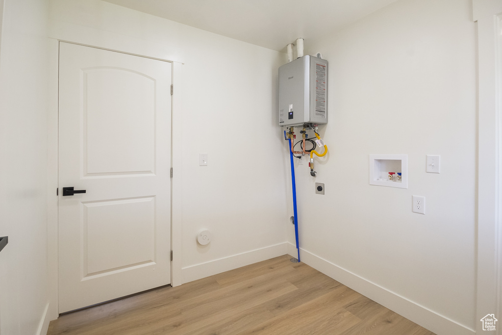 Laundry area with electric dryer hookup, light wood-type flooring, hookup for a washing machine, tankless water heater, and gas dryer hookup