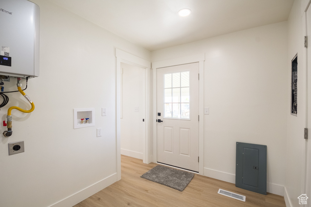 Washroom featuring electric dryer hookup, hookup for a washing machine, light wood-style flooring, and water heater