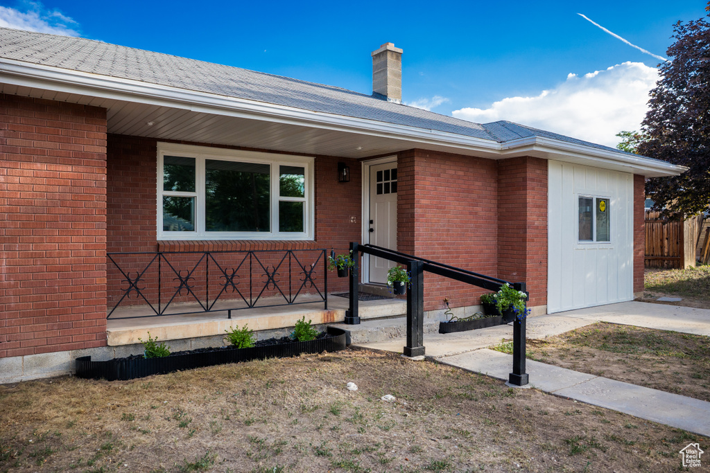 View of front of house with a chimney, brick siding, and a porch