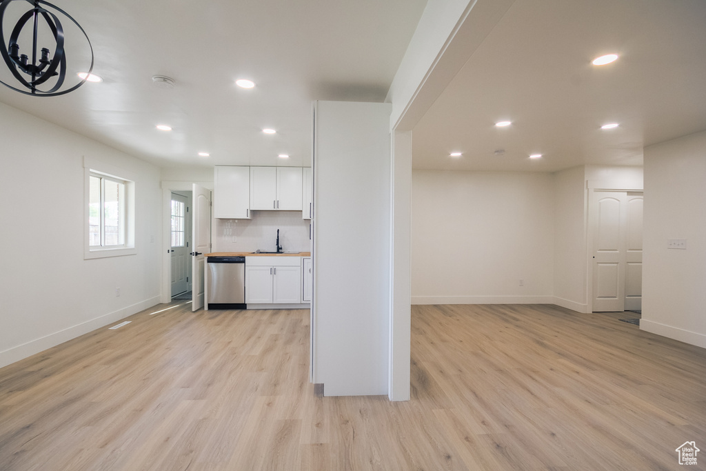 Kitchen featuring stainless steel dishwasher, white cabinets, recessed lighting, light wood-style floors, and a chandelier