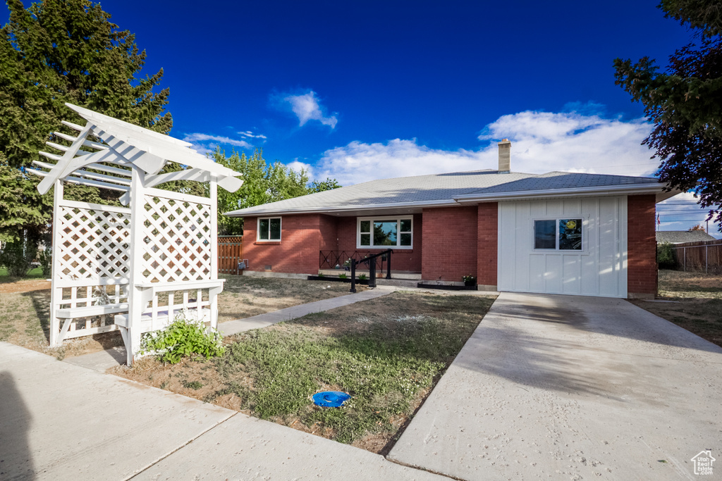 Ranch-style house with a chimney, concrete driveway, board and batten siding, and brick siding